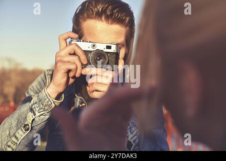 L'homme élégant photographier une femme sur appareil photo rétro dans la rue Banque D'Images