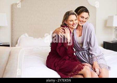 Mariage, dressing et mariée avec femme câlin dans la chambre à coucher pour cérémonie de mariage, événement social et célébration. Heureux, amour et demoiselle d'honneur avec personne Banque D'Images