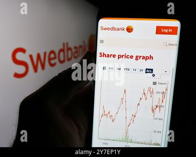 Allemagne. 23 septembre 2024. Dans cette illustration photo, une personne tient un téléphone portable avec le site Web de la société suédoise de services financiers Swedbank AB devant le logo. Crédit : SOPA images Limited/Alamy Live News Banque D'Images