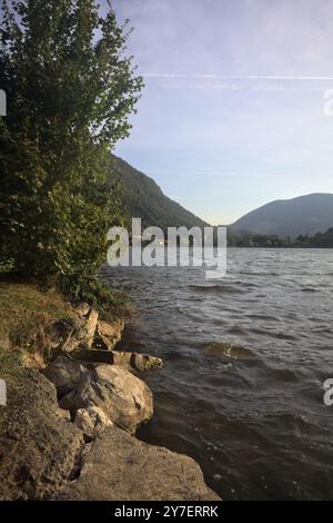 Lac dans les montagnes au coucher du soleil encadré par des plantes Banque D'Images