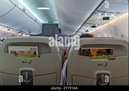 Riga, Lettonie - 7 septembre 2024 : les voyageurs sont assis dans un avion, prêts pour le décollage avec des écrans de divertissement en vol. Banque D'Images