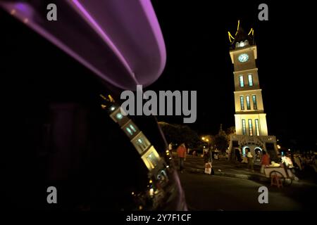 Grande tour d'horloge connue localement sous le nom de Jam Gadang et son reflet sur le verre de voiture, à Bukittinggi, Sumatra Ouest, Indonésie. Banque D'Images