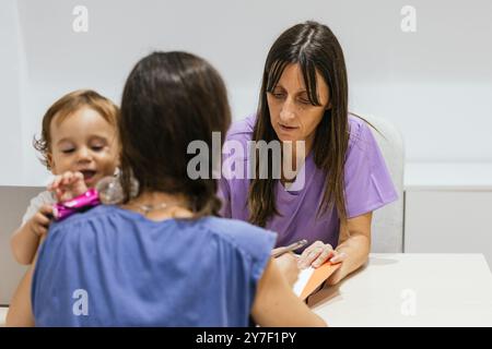 Médecin féminin prenant des notes tout en parlant avec la mère tenant bébé Banque D'Images