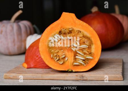 Citrouille Hokkaido coupée en deux montrant des graines sur une planche à découper dans la cuisine Banque D'Images