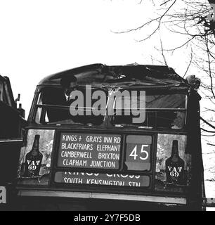 Accident de bus à Londres. Un bus de transport londonien n° 45 a été gravement damné quand il a été en collision avec une grue à Grays Inn Road, Holborn aujourd'hui. La grue était chassée d'une rue latérale dans Grays Inn Road lorsque la flèche a heurté le pont avant supérieur de l'autobus. Ici, un homme se penche pour inspecter la damamge. 4 avril 1962. Banque D'Images