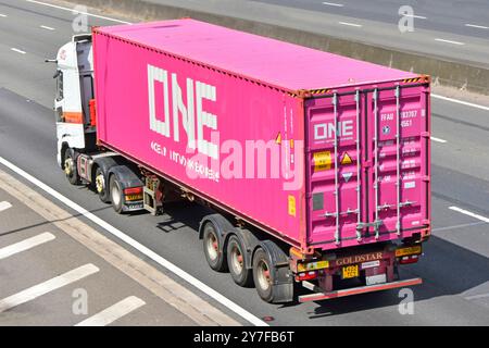 Vue arrière arrière arrière d'une ligne intermodale conteneur d'expédition rose et semi-remorque tractée par camion poids lourd camion moteur M25 autoroute route Essex Angleterre Royaume-Uni Banque D'Images