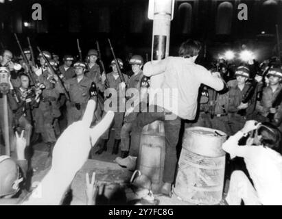 Des manifestants anti-guerre en conflit avec les gardes nationaux qui ont interrompu la Convention nationale démocratique. Photo : un hippie s'accroche à un poteau électrique lors d'une confrontation avec les gardes nationaux devant l'hôtel Conrad Hilton où d'autres manifestants donnent le signe de paix. Chicago, Illinois, États-Unis - 28 août 1968 Banque D'Images