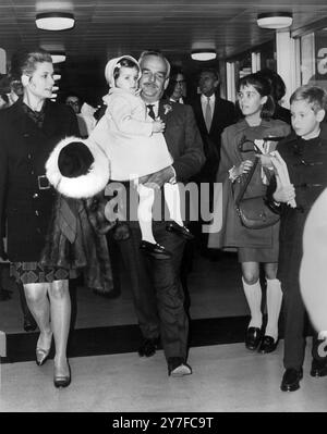 Le Prince Rainier III de Monaco transporte sa fille de trois ans, la Princesse Stéphanie, alors que lui et la Princesse Grace, née aux États-Unis, se sont envolés à l'aéroport de Londres depuis Madrid. À droite se trouvent les deux enfants aînés, le Prince Albert, 10 ans, et la Princesse Caroline, 11 ans. 31 octobre 1968 Banque D'Images