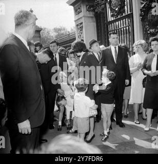 Sur la photo, bousculant à l'extérieur du palais de Buckingham lors de leur visite sont les enfants Kennedy et leurs proches parents. Vu ici : Caroline Kennedy (7) (bande alice blanche) et John Kennedy (4) (chemise blanche) enfants de Mme Jacqueline Kennedy, qui tient la main du petit Anthony Radziwell, fils de la sœur de Jackie, la princesse Lee Radzilwell, comme sa sœur Anna Christine se canard bas pour observer la tactique d'un chien (pas en photo). Mme Kennedy est ici pour le dévoilement du mémorial à son défunt mari et président américain à Runnymede. 13 mai 1965. Banque D'Images