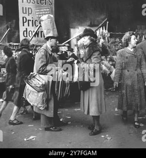 Un vendeur de sacs en papier pour les acheteurs harcelés à Brixton Market, Londres. Dans les jours précédant les sacs en plastique partout, les clients s'attendaient de plus en plus à avoir leurs courses dans des sacs en papier, créant une opportunité pour les entrepreneurs. - - - - Sac en papier sur la tête pour annoncer ses services - - - - 25 février 1950 Banque D'Images