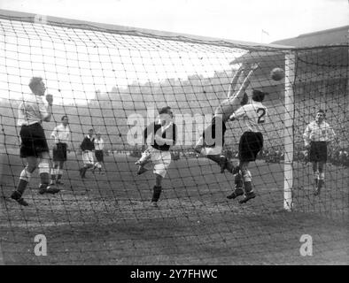 Écosse - Angleterre Bert Williams le gardien de but anglais étroitement soutenu par son capitaine Billy Wright arrière gauche et droit Alf Ramsey (2) se jette en arrière pour sauver d'une attaque écossaise menée par l'attaquant central Willie Bauld ( chemise noire au centre) dans le match international à Hampden Park Glasgow. A droite se trouve à l'intérieur gauche Roy Bentley de Chelsea qui a marqué le seul but du match pour donner à l'Angleterre la victoire et le championnat international du 16 avril 1950 Banque D'Images