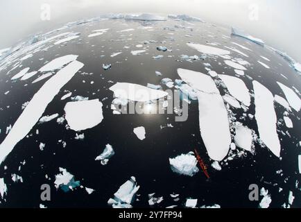 Une vue fisheye d'un kayak qui traverse les icebergs de la côte ouest de la péninsule de l'Antarctique connue sous le nom de Graham Land. Banque D'Images