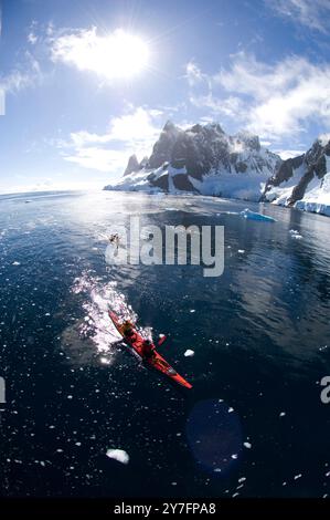 Les kayakistes pagayent dans l'eau bleue claire du canal Lemaire sur la côte ouest de la péninsule de l'Antarctique connue sous le nom de Graham Banque D'Images