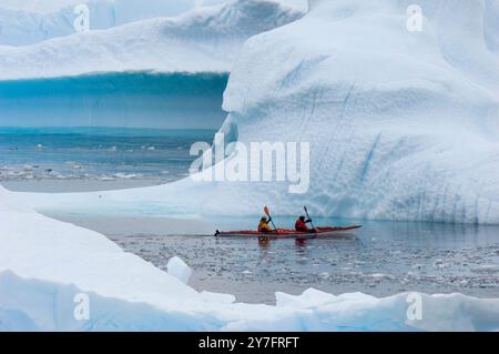 Deux kayakistes traversent les eaux glacées autour de l'île de Cuverville sur la côte ouest de l'Antarctique. Banque D'Images