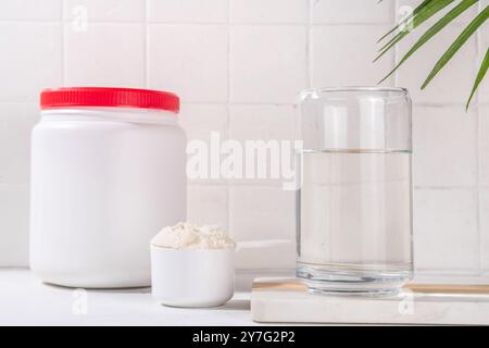 Poudre de protéine de collagène avec un verre d'eau sur la table de cuisine blanche. Supplément naturel pour la beauté, la santé de la peau, des os, des articulations et des intestins, anti Banque D'Images