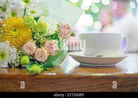 bouquet de belles fleurs à côté d'une tasse blanche de café, thé sur la table. Bonjour. Bonne journée Banque D'Images