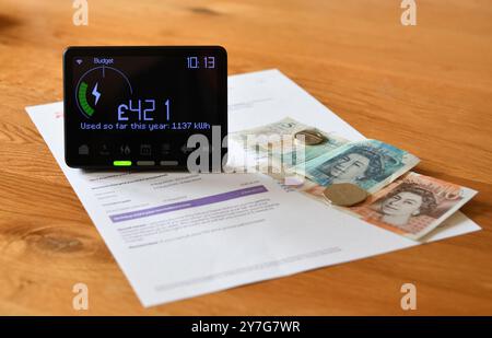 Compteur intelligent d'électricité dans l'affichage à la maison (IHD) sur la table en bois montrant le coût utilisé jusqu'à présent cette année en livres sterling et la consommation d'énergie en kilowattheures Banque D'Images