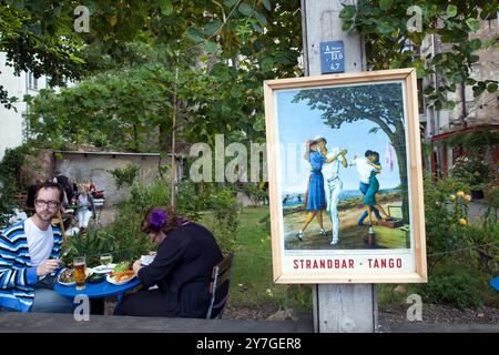 Les clients peuvent savourer de délicieux plats et boissons dans un restaurant avec patio confortable entouré d'une verdure vibrante dans le quartier animé du Scheunenviertel de Berlin. Banque D'Images