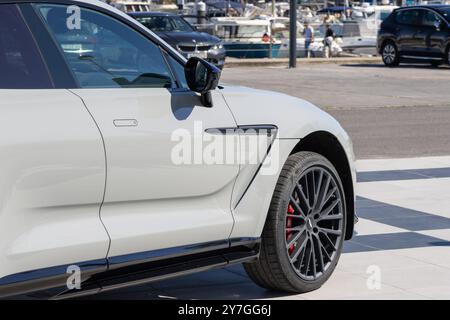 White aston martin dbx est garé près d'un port par une journée ensoleillée Banque D'Images