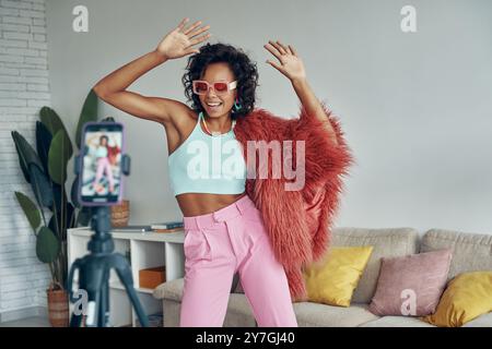 Femme africaine à la mode créant sa vidéo de danse sur la caméra du téléphone à la maison Banque D'Images