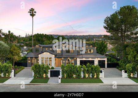 Une maison de luxe moderne avec une cour avant paysagée et un beau ciel de coucher de soleil en arrière-plan. Banque D'Images
