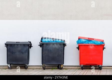 Trois conteneurs de déchets industriels néerlandais devant un mur avec espace de copie Banque D'Images