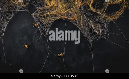 Toiles d'araignées dorées complexes fausses décorations de toile d'araignée d'halloween et araignées sur un fond grunge noir foncé, fond de thème de saison d'automne effrayant, Banque D'Images