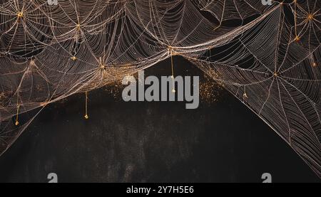 Toiles d'araignées dorées complexes fausses décorations de toile d'araignée d'halloween et araignées sur un fond grunge noir foncé, fond de thème de saison d'automne effrayant, Banque D'Images