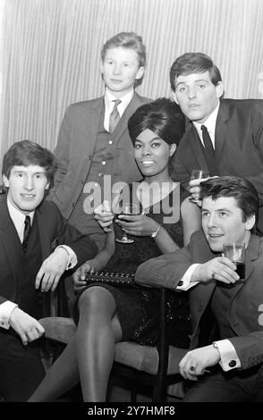 21 MAI 1964 regardez ce que les chercheurs ont trouvé. The Merseyside Beat Group -' The Searchers' photographiés à ATV House à Londres ce soir sont tous à proximité de la chanteuse américaine Dionne Warwick (22 ans), dont ils sont tous friands. Les garçons, de gauche à droite autour de Miss Dionne sont Chris Curtis, John McNally, Tony Jackson et Mike Warwick, une ancienne fille du New Jersey. Les Searchers ont ravé au sujet de ses disques, et eux, eux-mêmes, après la récente visite réussie aux États-Unis sont de retour dans quelques jours. Londres, Angleterre Banque D'Images