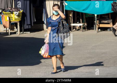 Femme marche dans la rue, cachant son visage du soleil Banque D'Images