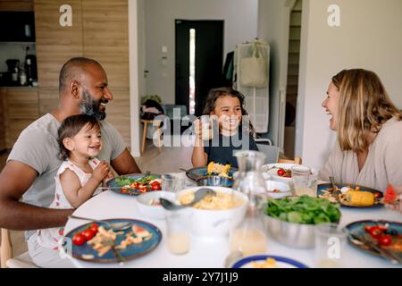 Famille heureuse appréciant le petit déjeuner tout en étant assis ensemble sur la table à manger à la maison Banque D'Images