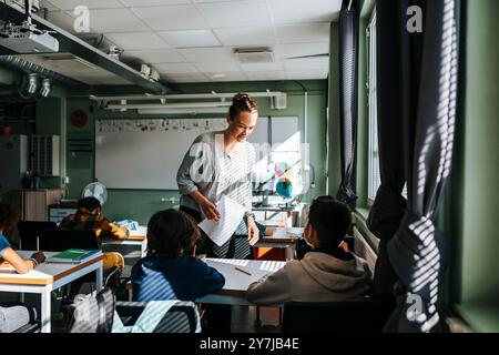Enseignante aidant un élève assis en classe à l'école Banque D'Images