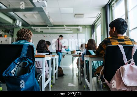 Sacs à dos suspendus sur une chaise avec des élèves assis dans la salle de classe à l'école primaire Banque D'Images
