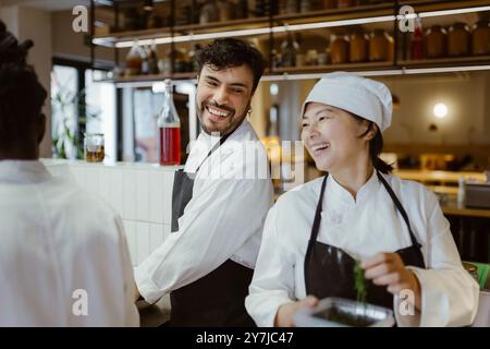 Chef mûr souriant appréciant avec un collègue masculin à la cuisine commerciale dans le restaurant Banque D'Images