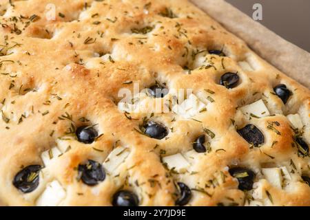 Pain focaccia fraîchement cuit garni d'olives, d'herbes et d'un soupçon de sel de mer. Idéal pour servir d'accompagnement, d'apéritif ou de cuisine gastronomique. Banque D'Images