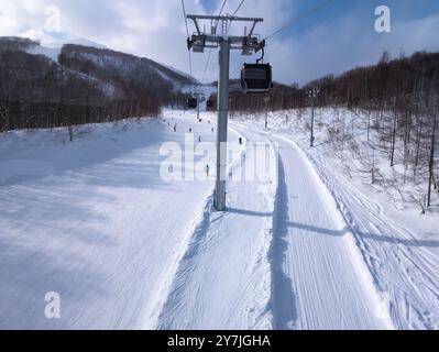 Ski ift gondoles et snowboarders sur une piste (Hirafu, Niseko) Banque D'Images