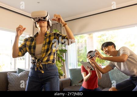 En utilisant un casque VR, mère profitant du jeu de réalité virtuelle avec la famille à la maison Banque D'Images