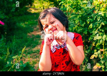 petite fille dans le jardin d'été posant parmi les fleurs. Photo de haute qualité Banque D'Images