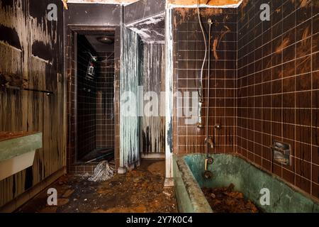 Un incendie a endommagé la salle de bain à l'intérieur d'une maison abandonnée avec des murs noircis. Cette maison a depuis été démolie. Banque D'Images