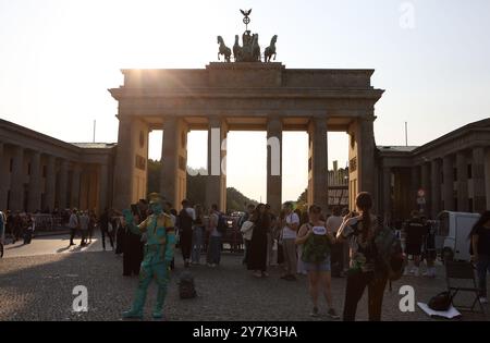 Touristes devant la porte de Brandebourg avec une sculpture en bronze d'une quadriga sur le dessus, célèbre monument allemand, rétroéclairé par le soleil de l'après-midi Banque D'Images