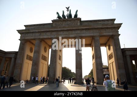 Touristes devant la porte de Brandebourg avec une sculpture en bronze d'une quadriga sur le dessus, célèbre monument allemand, rétroéclairé par le soleil de l'après-midi Banque D'Images