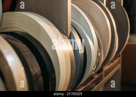 Gros plan de bobines de placage de bois, présentant une variété de finitions et de couleurs. Les rouleaux sont soigneusement disposés dans un atelier ou un réglage d'usine. Banque D'Images