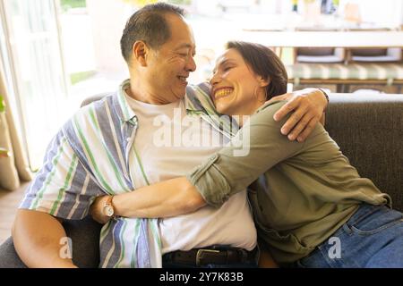 Femme souriante embrassant un homme plus âgé sur le canapé, profitant du temps de qualité en famille ensemble Banque D'Images