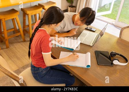 Etudiant ensemble, deux étudiants utilisant un ordinateur portable et une table de cahiers Banque D'Images