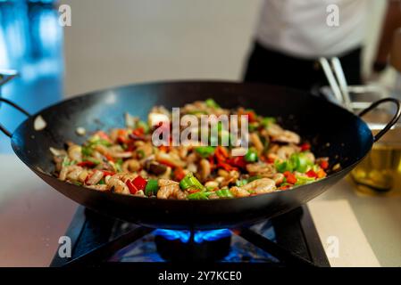 Le chef cuisine des crevettes avec des légumes dans un wok. Banque D'Images