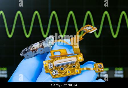 Pliez la carte de circuit imprimé à l'intérieur de la tête de lecture du lecteur de CD-DVD. Lentille, diode laser semi-conductrice ou puce de capteur sur câbles flexibles à la main d'un ingénieur. Banque D'Images