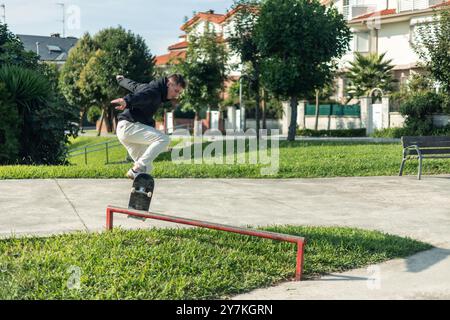 skateur qualifié copyspace planant au-dessus d'un rail rouge vibrant dans le skate park, mettant en valeur leur technique impressionnante et leur confiance. Le moment est en surbrillance Banque D'Images