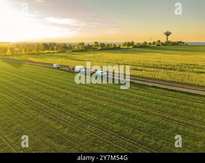 Vue aérienne de larges champs avec plusieurs véhicules garés sur une route, scène paisible au coucher du soleil dans la campagne, installation de fibre optique, Calw distric Banque D'Images