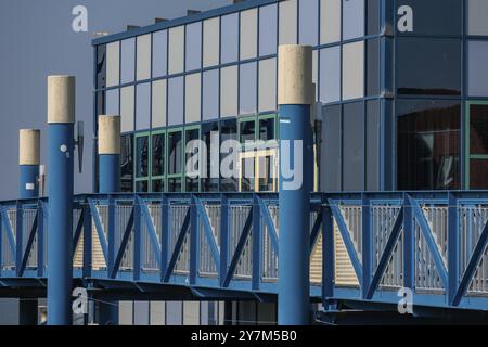 Gros plan d'un bâtiment moderne avec pont bleu et façade en verre, reflétant au soleil, norden, norddeich, mer du Nord, allemagne Banque D'Images