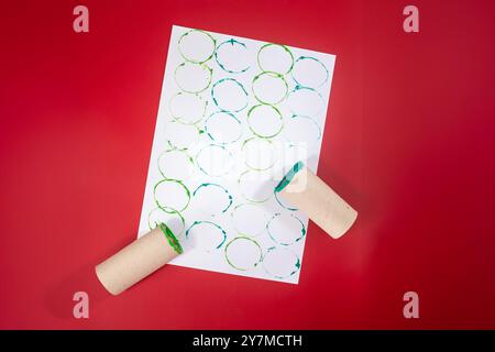 Cartes de Noël festives avec des motifs circulaires verts personnalisés. Les timbres fabriqués à partir d'un rouleau de papier toilette et de peinture créent des designs originaux pour le papier d'emballage ou les cartes de voeux dans ce projet de vacances DIY. Banque D'Images